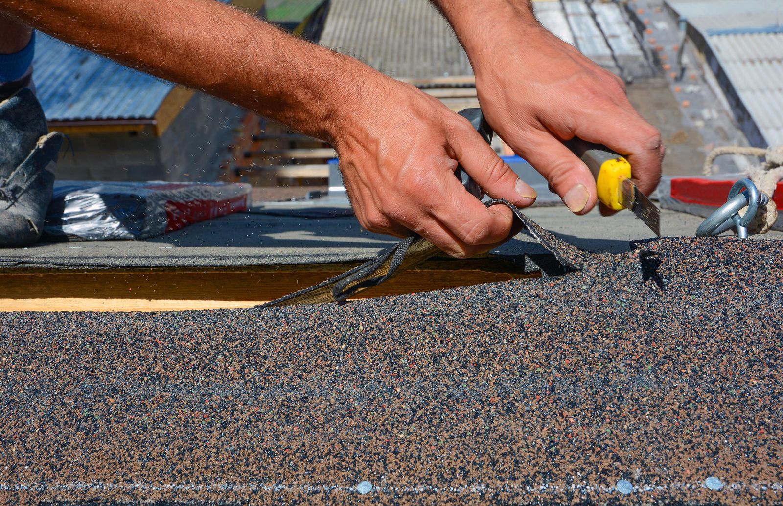 Roofer cutting shingles at the ridge
